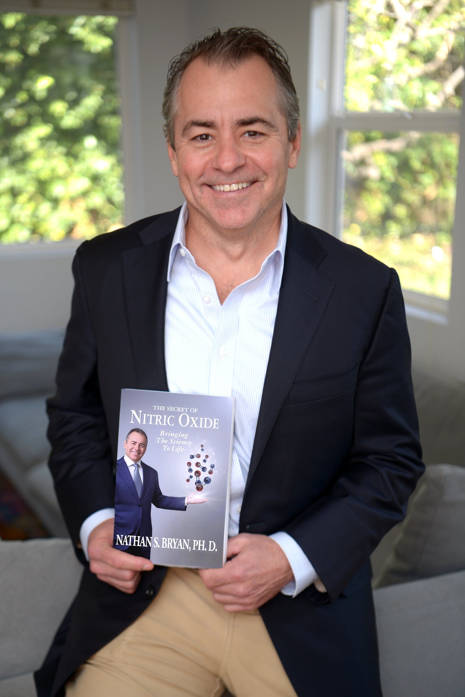 Man holding a book titled 'Nitrile Oxide' by Nathan Bryan in a well-lit room.
