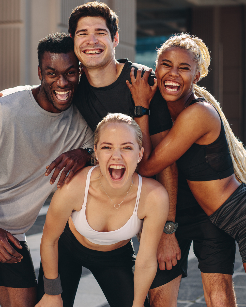 Four people posing together outdoors, smiling and laughing.