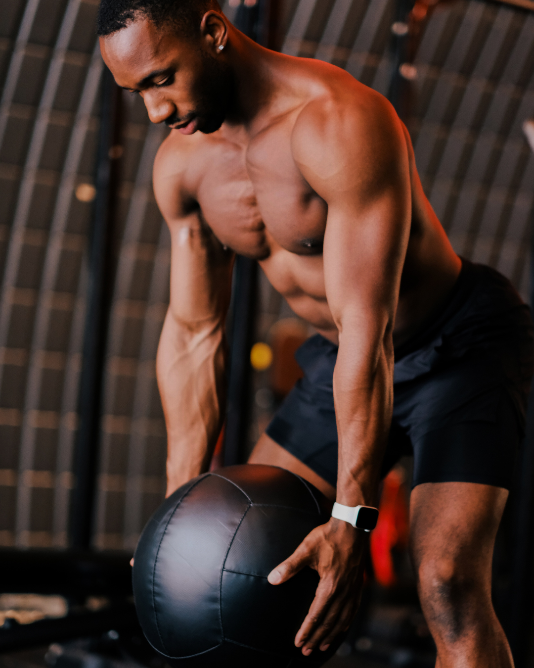 Muscular man holding a medicine ball in a gym setting