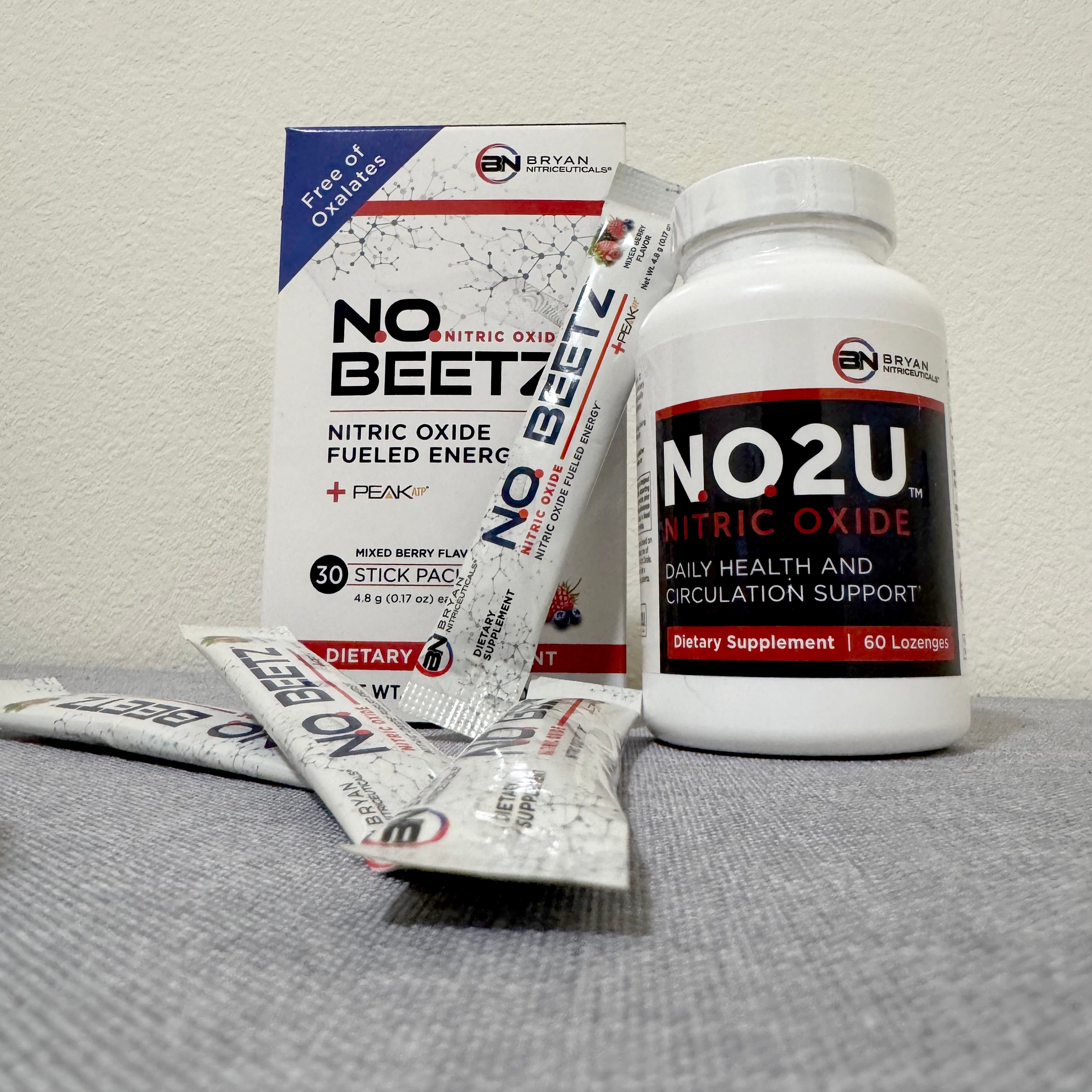 Supplement products including 'NO Beet' and 'NO2U' on a gray surface with a neutral background.