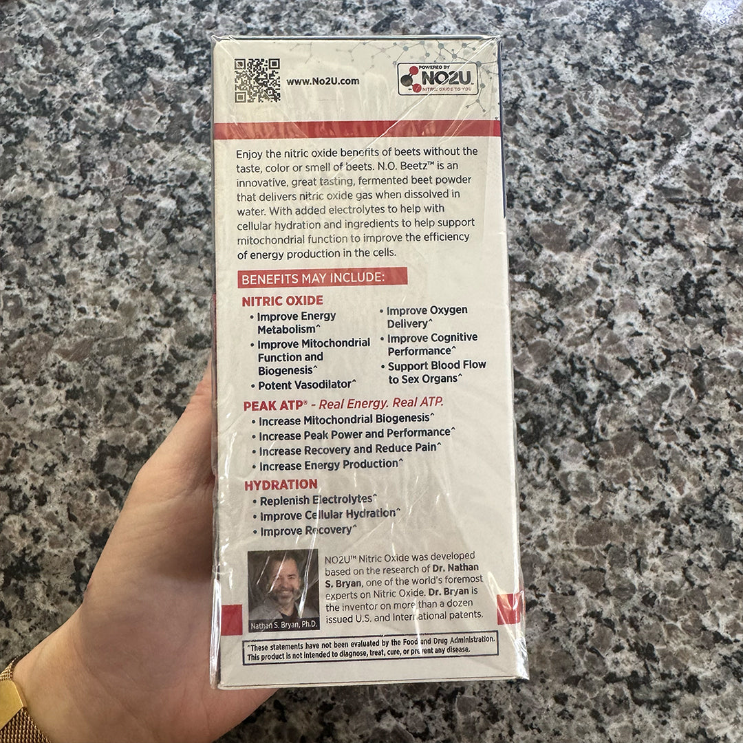 Hand holding N.O. Beetz box with benefits and branding on a granite countertop